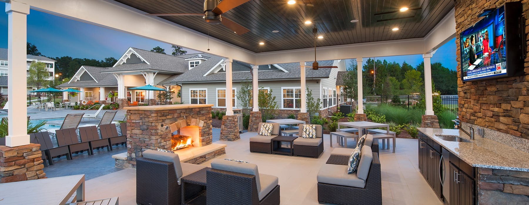outdoor lounge area with a fireplace, ample seating and nearness to swimming pool